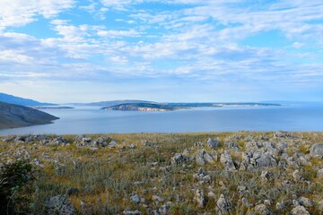 View of Rab island in the Adriatic sea from a meadow with rocks at Krk in Kvarner, Croatia