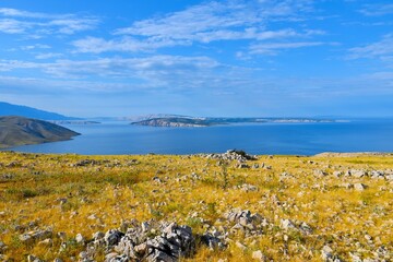 Rocky meadow with dry grass at Krk island with Rab island in the distance in Kvarner, Croatia