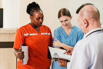 Medical team reviews patient records during hospital shift change. Nurses and doctors collaborate with charts in hand, emphasizing teamwork, communication, and quality healthcare service.