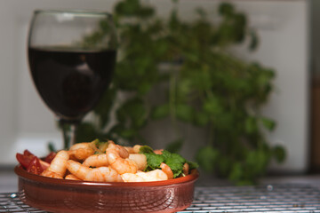 Shrimp baked with garlic and butter in a bowl. Wooden background. Side view. Hot chili with garlic. Shrimp cooked with herbs, seafood, shellfish, scampi in a brown bowl