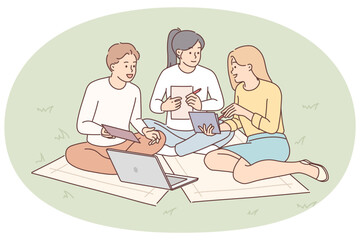 Students are sitting on lawn with laptop preparing joint extracurricular activity assigned