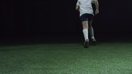 Young man playing football and running on the green grass field - Powered by Adobe