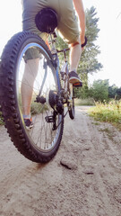 Cyclist rides mountain bike sunset trail rural field. Young man riding on bike in the countryside. Back view. Active summer holidays.