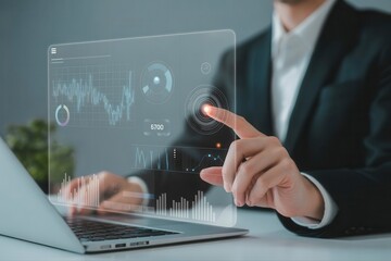 Businessman interacts with futuristic digital interface, analyzing data on a transparent screen using a laptop computer.