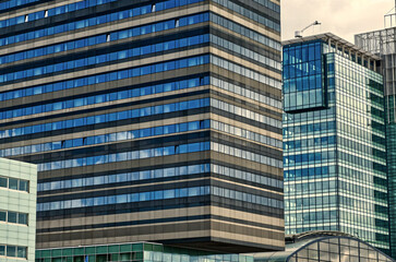 Clouds reflecting on the sleek glass facades of modern buildings in amsterdam's bustling financial district create a stunning urban scene