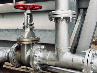 pipes and valves. Close-up of industrial pipeline system with red-handled valve and pressure gauge....