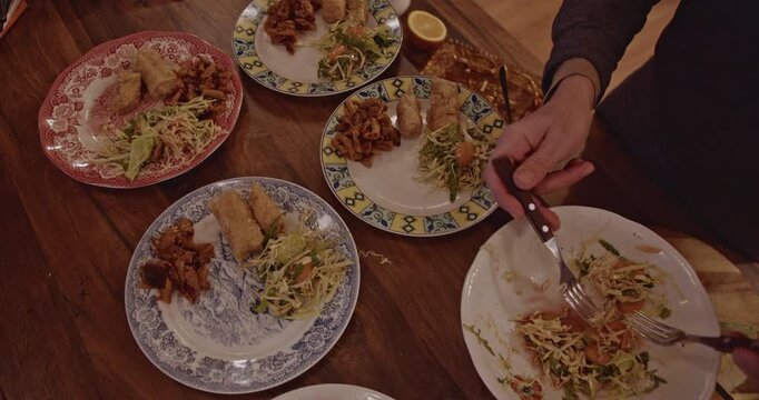 Friends gather around a wooden table, enjoying a meal together. They share food and conversation, creating a warm and inviting atmosphere.