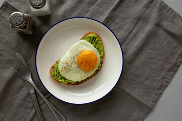Homemade Avocado Toast with Egg on a Plate, top view. Space for text.
