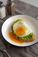 Homemade Avocado Toast with Egg on a Plate, side view. Close-up.