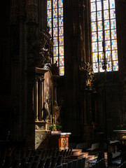 Interior of St. Stephen's Cathedral in Vienna with sunlight on altar and colorful stained glass.