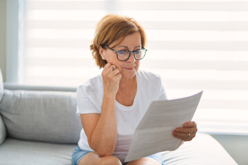 mature senior woman check bill on sofa