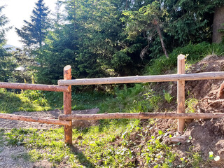 A rustic wooden fence in a lush forest setting.