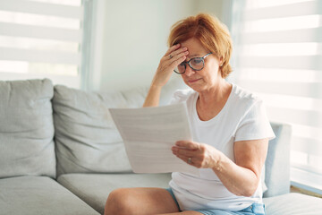 Fototapeta premium mature senior woman check bill on sofa