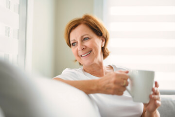 mature woman drink coffee on sofa at home