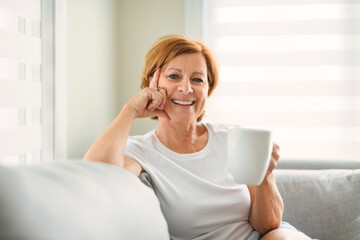 mature woman drink coffee on sofa at home