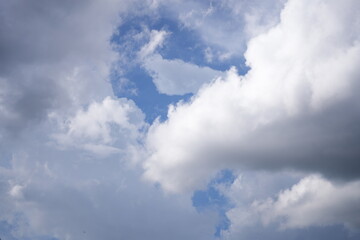 Bright blue sky with soft white clouds scattered across a clear day, evoking a sense of peace and...