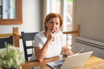 Sad frustrated senior woman pensioner having depressed look, holding hand on her face, calculating...