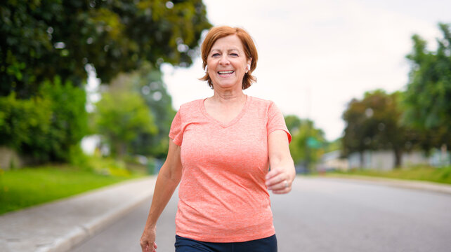 Woman fast walking outdoors with wireless headphones