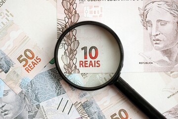 Brazilian reais banknotes and magnifying glass. The current Brazil real money bills and loupe