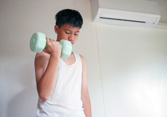 Exercise & Wellness, Youngster doing exercise with dumbbell, Asian teenage boy in white tank top exercising with dumbbells at home