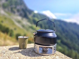 Enjoying a hot drink amidst majestic mountains, where green slopes meet the blue sky, creating a...
