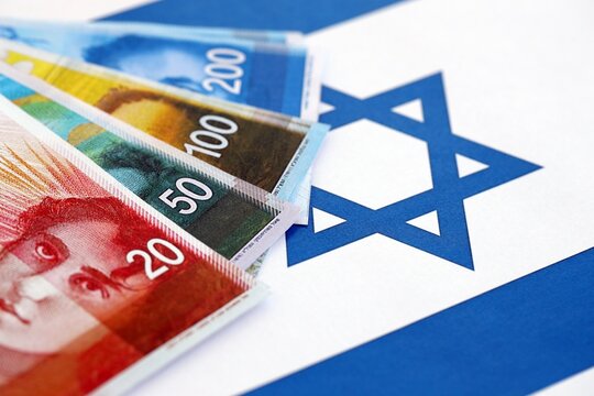 Israel New Shekels banknotes on national flag. The current Israel money bills lies on flag