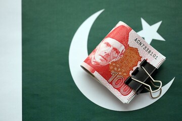 Pakistan rupees banknotes on Pakistani flag. The current Pakistan money bills