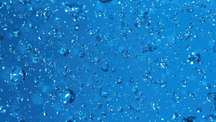Water droplets scattered on a vibrant blue background creating a textured and refreshing visual effect