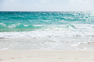 Waves wash up on white beach sand