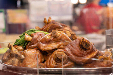 A large serving tray filled with braised pork knuckles and pork hocks. The pork has been slow-cooked or braised until tender, usually in a savory and slightly sweet soy-based sauce.