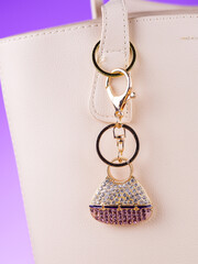 Close-up of a metal bag charm with rhinestones in the shape of a women's handbag on a table   on...