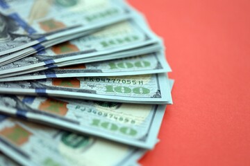 Big amount of United States hundred dollar bills on red background