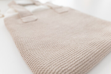 Soft beige tote bag resting on a clean, bright surface with subtle textures and details