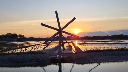 Windmill for salt pond liquefaction industry in the afternoon during summer with sunset sky background at Pamekasan, Indonesia.