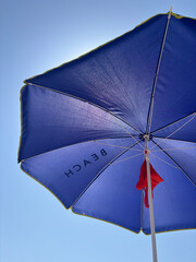 Blue beach umbrella providing shade on sunny day