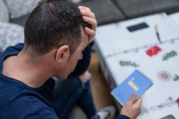 Frustrated man running out of ideas holding notebook at home