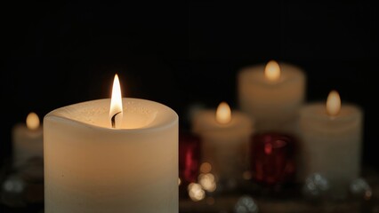 A solitary candle glowing brightly in the night surrounded by other dimly lit candles
