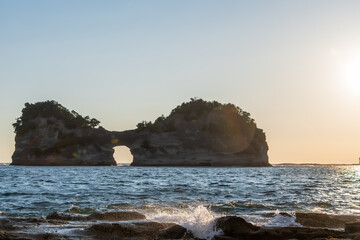 夕日に染まる円月島と太平洋の波