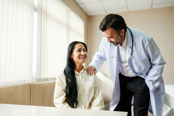 Smiling patient consults with a caring primary care doctor during a routine hospital visit. Scene...