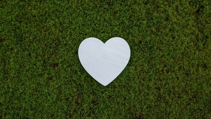 White fabric heart shape placed on vibrant green mossy surface creating a contrast of textures and colors in a natural setting
