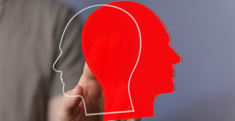 Stock photo depicting two head silhouettes, one red, one transparent, symbolizing different...