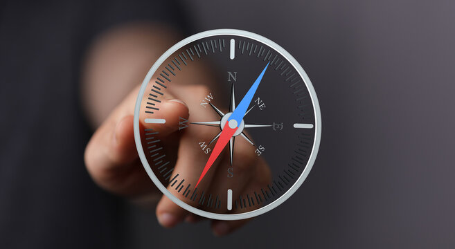Close-up of a hand interacting with a digital compass interface, symbolizing direction and guidance.