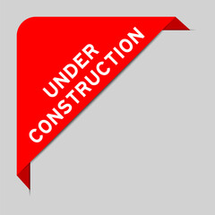 Red color of corner label banner with word under construction on gray background