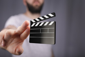 Close-up of a man's hand holding a digital clapperboard, symbolizing filmmaking and video...