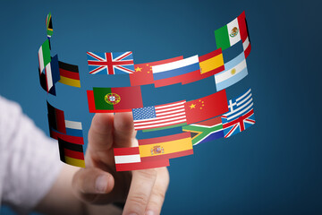 Image of a hand interacting with a digital display of various national flags, representing global...