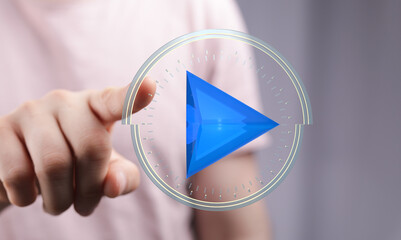 Person interacts with a futuristic digital play button interface. Technology, media, and innovation...