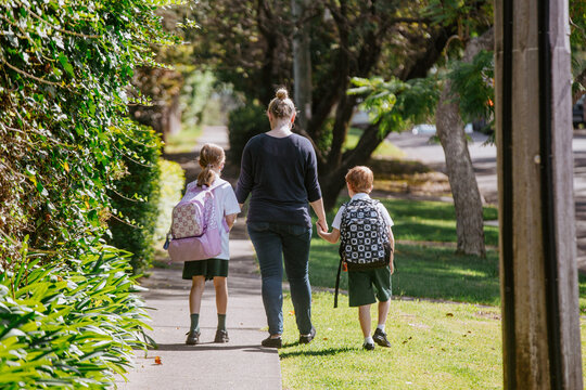 Mother holding hands with her children on walking path