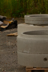 A large stack of heavy concrete rings is carefully placed on top of a sturdy wooden pallet, ready...