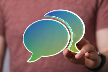 Image of a hand holding digital speech bubbles, representing communication, conversation, and...