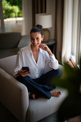 Attractive middle aged woman using her cellphone at home
